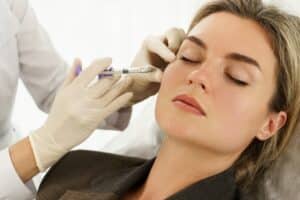 Woman receiving dermal filler injections in her face for a smoother, blemish-free skin.