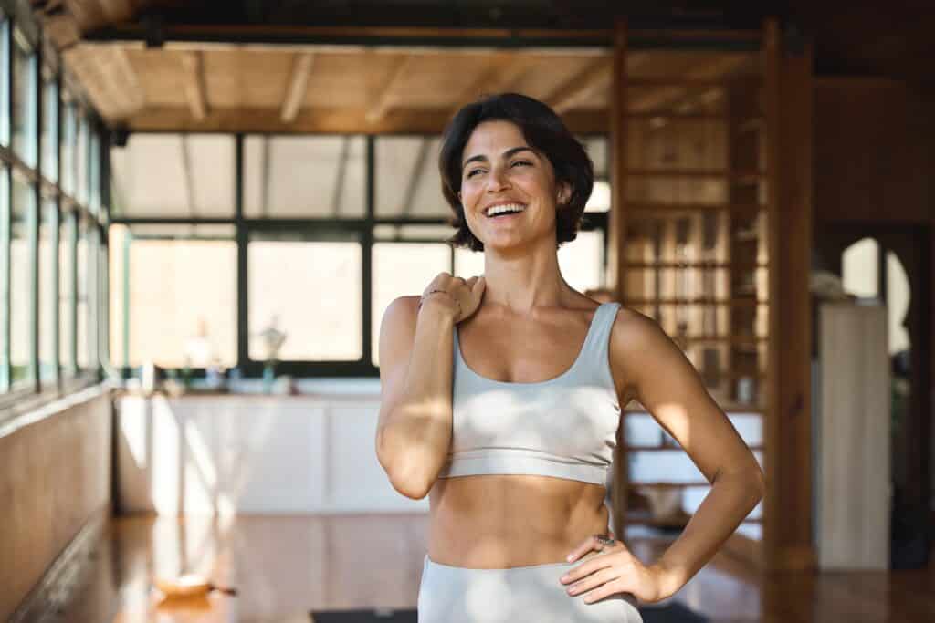 Woman smiling in yoga studio looking fit from EmSculpt Neo in Los Angeles