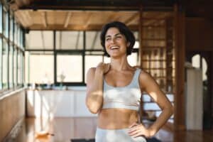 Woman smiling in yoga studio looking fit from EmSculpt Neo in Los Angeles