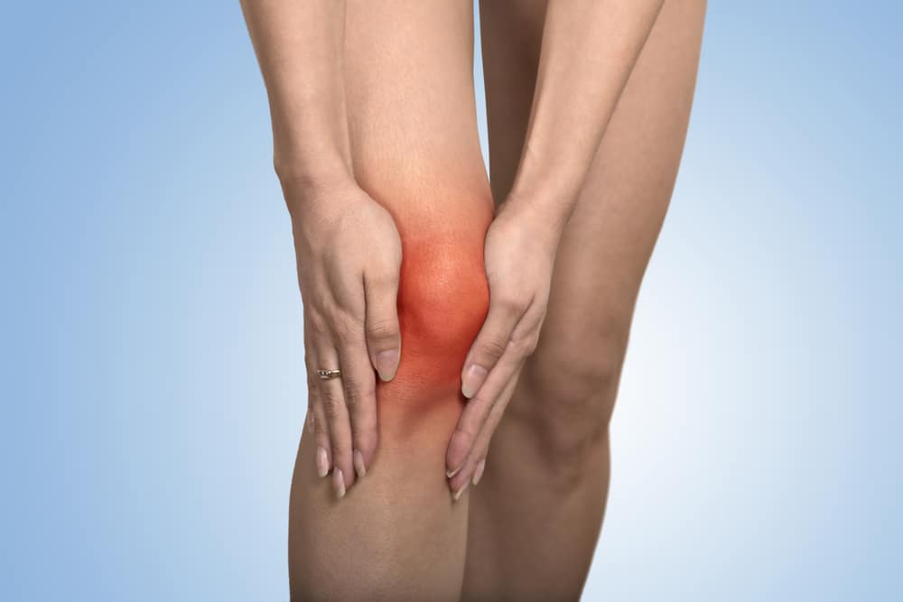 Close up of woman's legs as she holds them due to varicose veins in Los Angeles, CA Person holding an aching knee, representing unexplained leg pain that may occur without recent exercise.